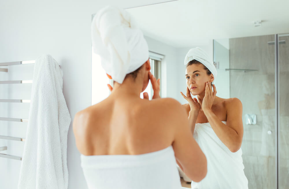 Woman checking her skin in the bathroom