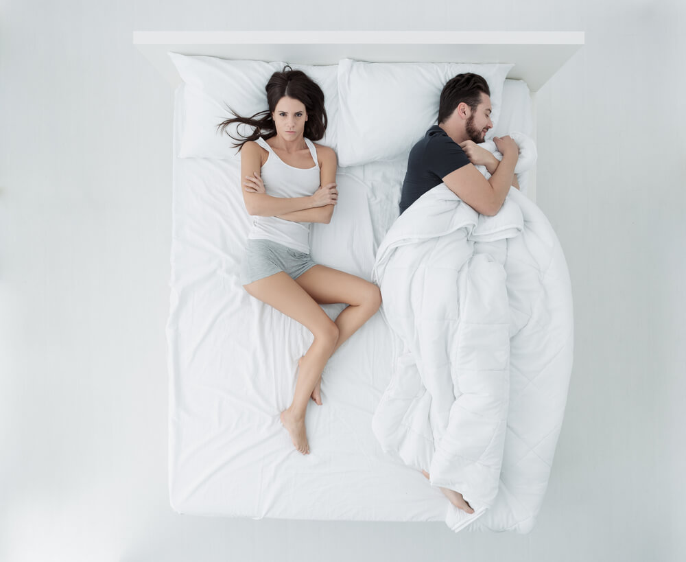 Couple in bed and woman has no blanket