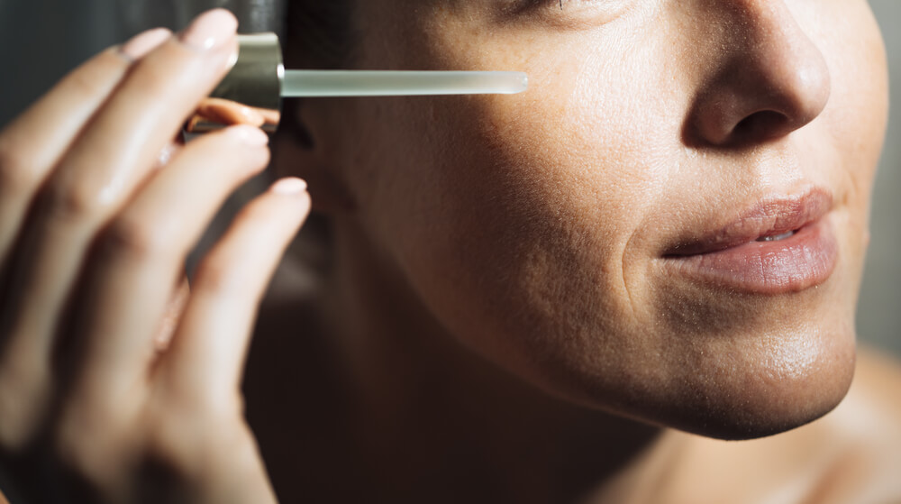 Woman applying face serum from dropper