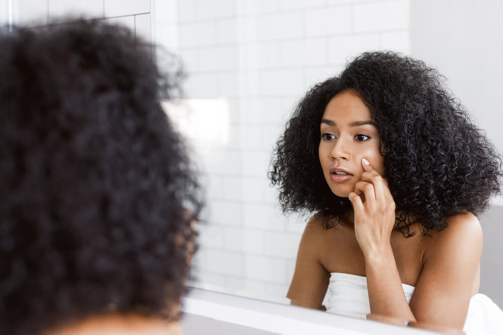 Woman looking at skin in mirror