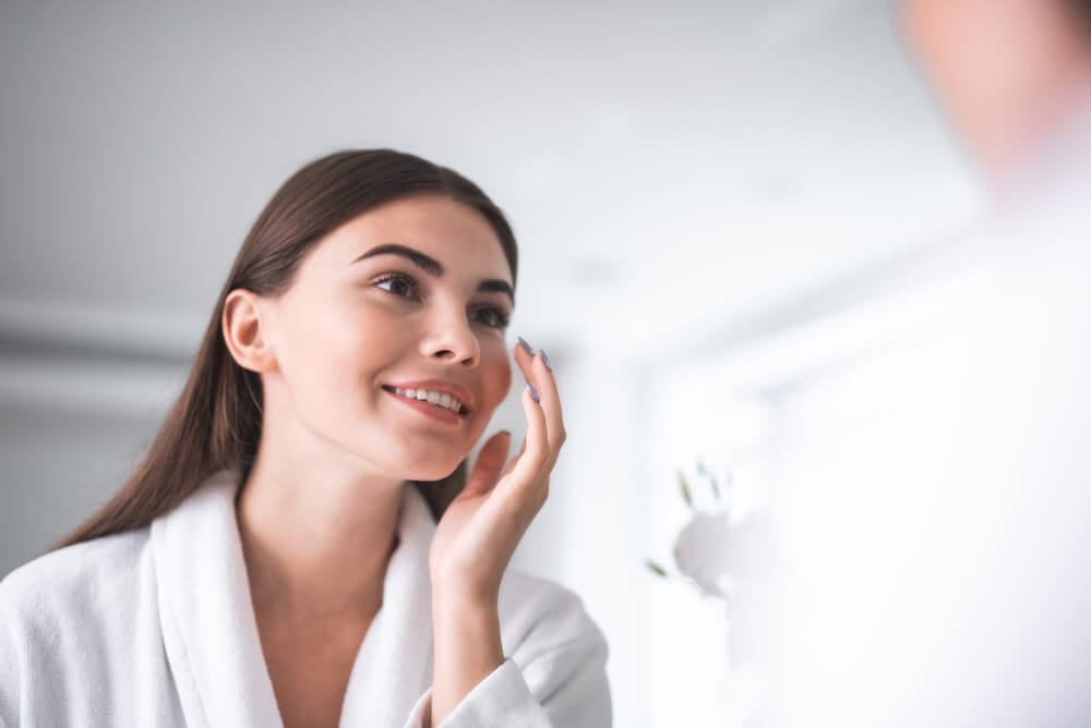 Woman looking at skin in mirror