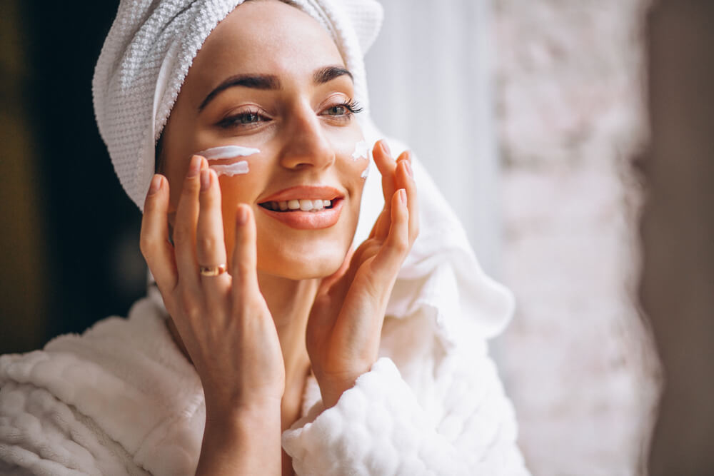 Woman applying OROGOLD 24K Deep Moisturizer to her face