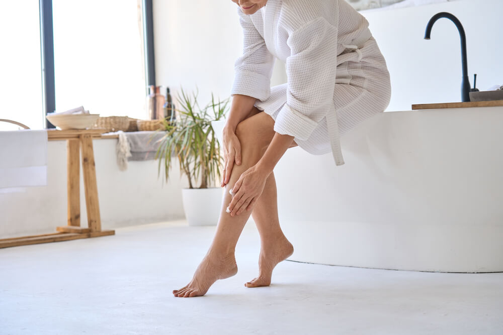 Woman applying lotion to legs